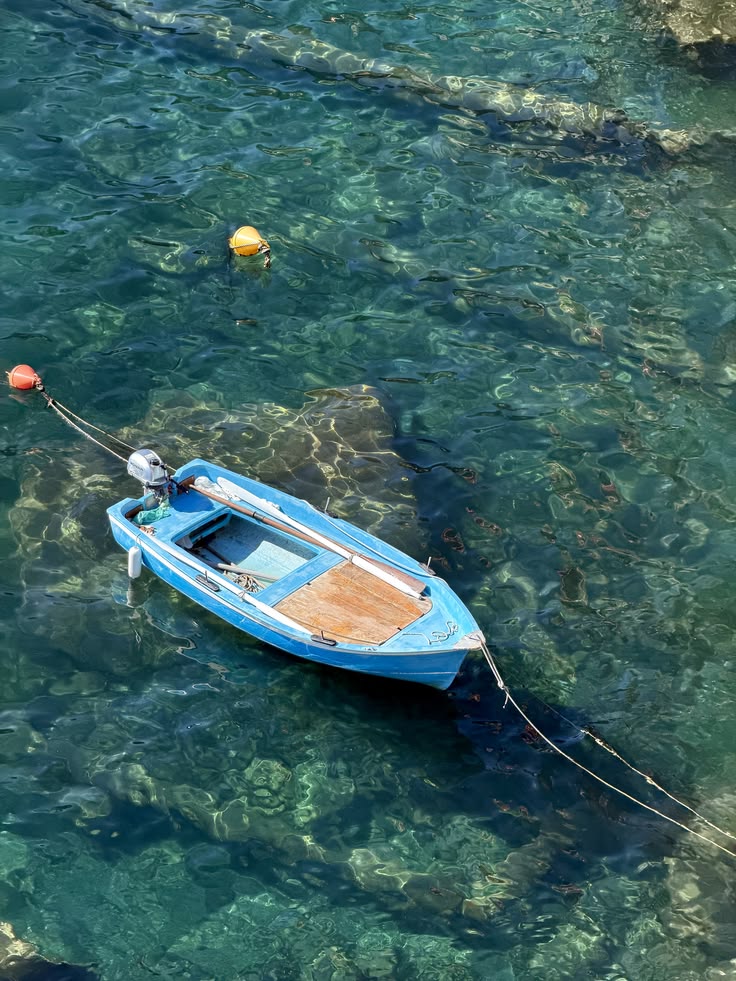 Blue wooden boat moored on clear turquoise Mediterranean water